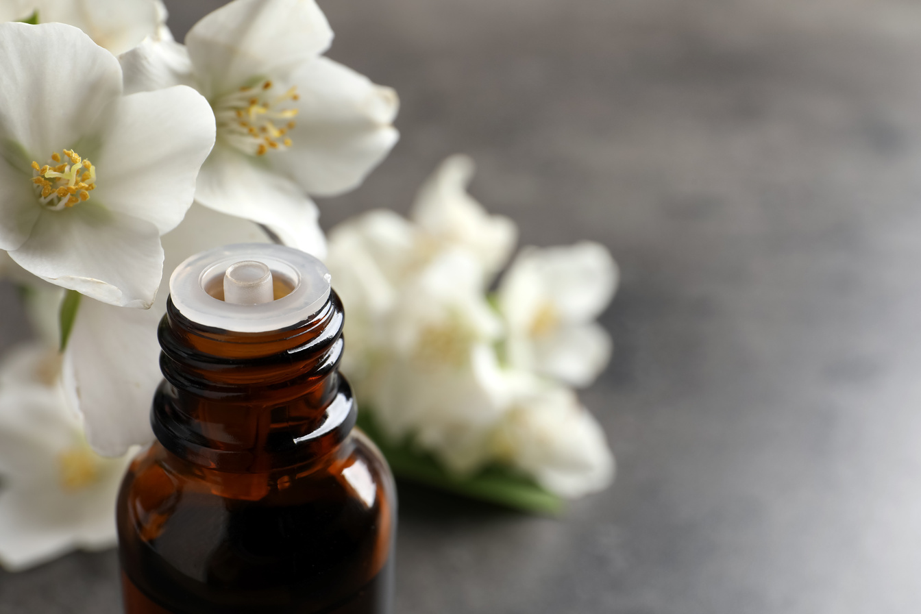 Essential Oil and Jasmine Flowers on Grey Table, Closeup. Space